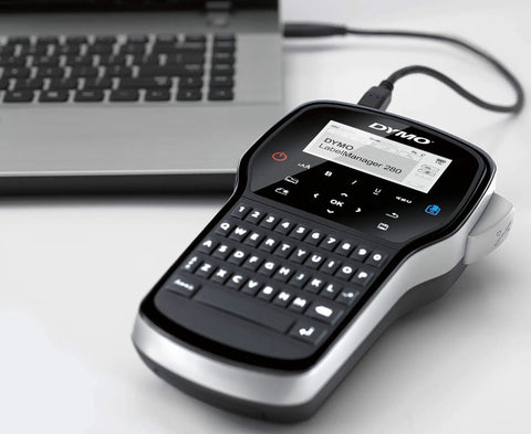 Grab And Go Portable Label Maker With Rechargeable Battery And Qwerty Keyboard next to a laptop, showcasing its compact design.