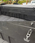 Acrux7 toolbox with rubber latches in a pickup bed; close-up shows a metal T-handle draw latch.