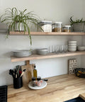 Heavy Duty Floating Shelf Brackets Fifty Eight Inches Long Invisible Mantel Supports For Thick Lumber Boards Matte Black Alloy Wall Mount Holders with potted plants and kitchenware.