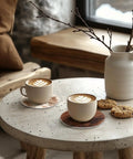 Premium Round Cowhide Coasters Set Of Twelve Natural Leather Drink Mats, two cups of coffee on stone table with cookies.