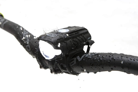 Swift 500 Front Bike Light on handlebars, showing USB rechargeable LED headlight, water droplets visible, for night cycling safety.