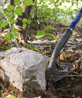 Heavy Duty Shovel With Fiberglass Handle 57 Inch Spade For Gardening, Trenching in soil next to a rock in a garden setting