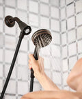 Person using Magnetix Six-Function Detachable Handheld Showerhead With Magnetic Docking System In Mediterranean Bronze Finish 3.5 Inch Face