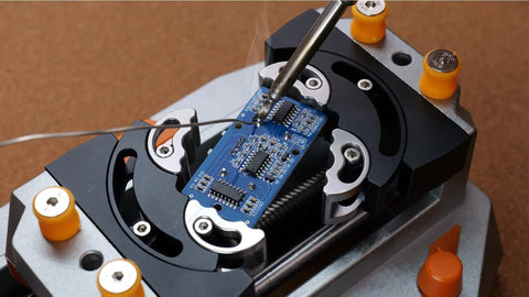 Desktop Mini Vise Dope For Soldering And DIY Projects With Adjustable Grip And Built In Lighting Magnifying Glass Attachment Smoke Exhaust Fan Ideal For Electronics Fine Crafting Repairs And Delicate Assemblies securing a blue PCB