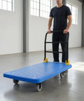Heavy Duty Foldable Flatbed Trolley Built Like A Tank With A Tough Perforated Deck And Six Inch Braked Casters For Smooth Rolling Shop Chores Or Straight Up Office Gear Moving In Robust Red being used in a spacious area.