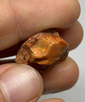 Raw Fiery Jalisco Mexican Fire Opal Stone For Jewelry Making Multicolor Natural Opal Rough Gem With Size 18mm By 16mm By 9mm And Weight 22.60 Ct From Jalisco Mexico Perfect For Beads Cabochons Or Pendant Projects For Unique Jewelry held in fingers