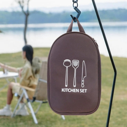 12 Piece Outdoor Camping Cookware Set Stainless Steel Portable Kitchen Tools bag hanging with lake view in background.