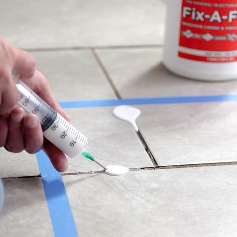 Person using syringe to apply Two Pack Loose Tile Repair Adhesive With Syringe For Tile Porcelain Ceramic Marble Stone And Wood Floors Extra Strength Bonding That Rebounds Loose Or Hollow Tiles Without Demolition on tiled floor