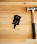 Heavy Duty Adjustable Furniture Leveling Feet With Right Angle Side Mount next to a hammer on wooden floor