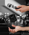 Boss Level 58Mm Espresso Tamping Station With Slick Anti Slip Base And Quick Adjustable Frame For Hassle Free Coffee Tamping Plus Nifty Grounds Catch Tray in use, handheld.