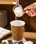 Pouring milk into No Sleeve Needed 12 Oz Ripple Wall Corrugated Insulated Paper Cups With Anti Scald Grip For Hot Or Cold Drinks Great For Office Cafe Party Or Travel 120 Pack