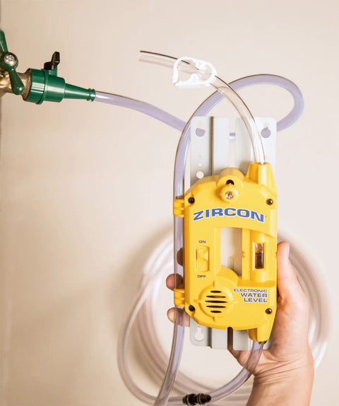 Bright yellow Electronic Water Level 25 Contractor Kit with 50 ft hose attached to wall for leveling up to 50 feet.