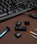 Nine Piece Keyboard Lube And Switch Extraction Kit With IC Extractor Key Cap Puller, tweezers, brushes on a keyboard