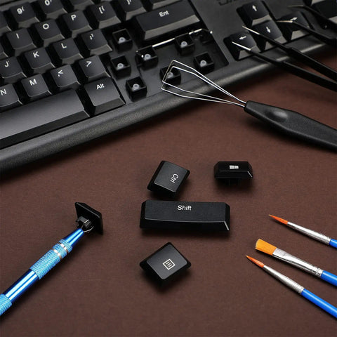Nine Piece Keyboard Lube And Switch Extraction Kit With IC Extractor Key Cap Puller, tweezers, brushes on a keyboard