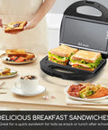 Aigostar Flat Sandwich Maker With Nonstick Deep Grill Surface, Black cooking crispy sandwiches on a table with breakfast items.