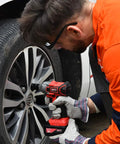 Man using Cordless 21V Half Inch Brushless Impact Wrench With 3.0Ah Battery And Fast Charger on car tire lug nuts