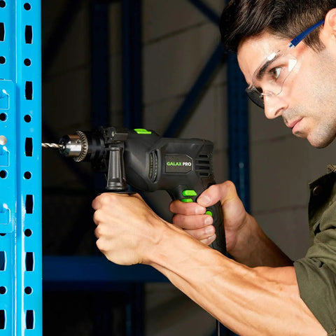Person using Pro-Grade 5 Amp Half Inch Hammer Drill Kit With 105 Accessories on metal shelving, close-up of drill in action