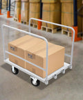 Heavy Duty Platform Truck Cart With Rock Solid Steel Deck And Smooth Roll Casters Built To Shift Two Thousand Pounds Like A Pro Warehouse Workhorse For Daily Hauling Tasks with cardboard boxes on it.