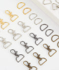 Straight Up Badass Swivel Snap Hooks And D Rings, Heavy Duty Zinc Alloy Keychain Clips And Craft Gear, Pack Of One Hundred Silver Finish For Outdoor Adventures laid out with gold, silver, and bronze clips and rings