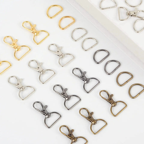 Straight Up Badass Swivel Snap Hooks And D Rings, Heavy Duty Zinc Alloy Keychain Clips And Craft Gear, Pack Of One Hundred Silver Finish For Outdoor Adventures laid out with gold, silver, and bronze clips and rings