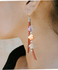 Earring featuring drilled glass spacer beads with purple and orange tones, combined with leather accents for DIY jewelry making.