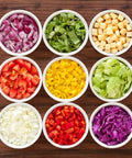 Amazin Goods All-in-One Vegetable Chopper; top-down view of nine bowls filled with chopped vegetables on a surface.