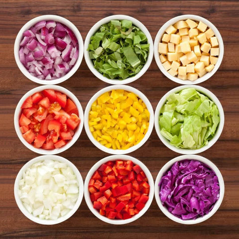Amazin Goods All-in-One Vegetable Chopper; top-down view of nine bowls filled with chopped vegetables on a surface.