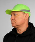 Side view of a man wearing a neon green reflective baseball bump cap hard hat safety helmet with breathable lightweight design.