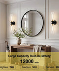 Battery Operated Wall Sconces Set of Two, Black and Gold Wall Light fixtures with Wireless Remote Control，Rechargeable Dimmable Wall Sconces with 3000K Bulbs for Bathroom Mirror Living Room Bedroom next to a round mirror.