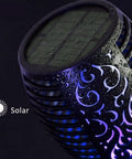Close-up of a Solar Tiki Torch Light with intricate pattern, purple glow, and solar panel, part of an eight piece set