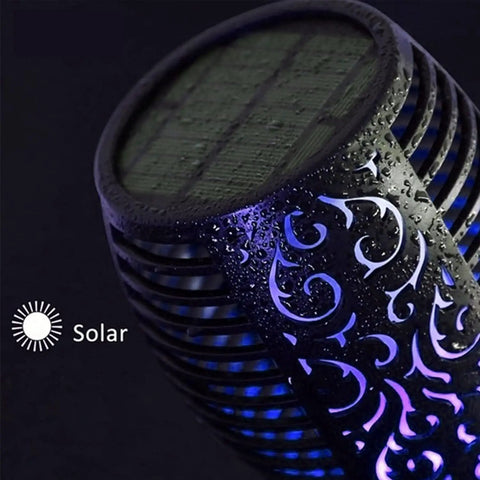 Close-up of a Solar Tiki Torch Light with intricate pattern, purple glow, and solar panel, part of an eight piece set