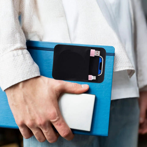 Stick On Dual Pocket SSD Carrying Case With Reusable Adhesive for laptops shown holding cables on blue tablet.