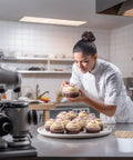 Chef decorating cupcakes with frosting in a modern kitchen, featuring Top Shelf Food Safe Mini Popsicle Sticks For Crafting Great Treats.