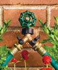 Heavy Duty Brass Dual Outlet Faucet Adapter Lets You Split One Faucet Into Two Hose Outlets With Separate Ball Valve Levers For Easy Flow Control Durable Brass Construction Handles High Water Pressure Brown Finish attached to wall with two hoses