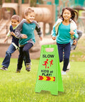 Slow Kids At Play Signs For Street Double Sided With Reflective Tape High Visibility Children At Play Safety Sign For Neighborhoods Schools Parks Sidewalks And Driveways 2 Pack Green on grass with children playing
