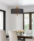 Alondra 20 Inch Modern Drum Gold Chandelier With Large Black Linen Shade 3 Light Modern Farmhouse Hanging Pendant Ceiling Light In Warm Brass Finish For Living Room Kitchen Island in a dining setting.