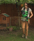 Person using Lithium Ion Chest Spreader With Harness System, Adjustable Feed Rate, 24 Volt Power, 35 Pound Hopper, on lawn