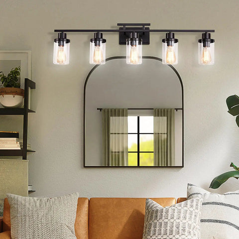 Five Light Black Vanity Fixture With Clear Glass Shades illuminating a bathroom mirror, modern farmhouse style, warm light.