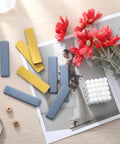 Eight Piece Premium High Density Self Adhesive PTFE Rectangle Furniture Glides on a wooden surface with flowers and decor.