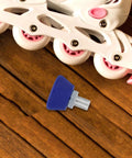 Two Pack Roller Skate Toe Stops And Toe Plugs Adjustable Five Eighth Inch Rubber Stops For Quad Skates Replacement Parts In Bright Blue on wooden surface beside white roller skate.