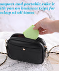 Hand placing green case of 20 Pack Mini Travel Sewing Kit Set For On The Go Repairs with Scissors Needles in black purse