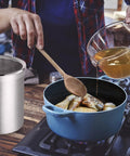 Stainless Steel Jumbo Grease Container With Removable Strainer And Snug Lid next to person pouring oil into pot on stove