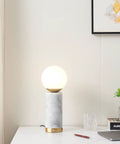 Aspen LED Table Lamp With USB Port For Bedside Or Desk Ambient Lighting And Marble Finish Globe Shade next to books and decor
