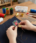 Hands using Big Eye Sewing Needles Kit 36 Pcs Stainless Steel with Storage Box to sew flower patch on fabric.