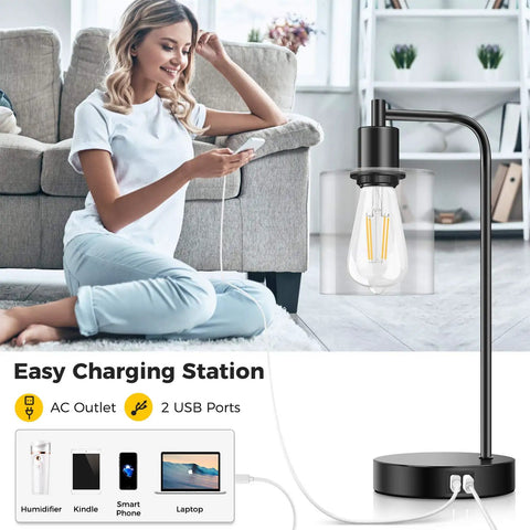 Set Of 2 Industrial Touch Control Table Lamps With 2 USB Ports And AC Outlet shown on table next to sofa with woman using phone