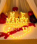 Romantic Marry Me Light Up Letters Proposal Kit with 7 letter signs, LED tea lights, burgundy rose petals, and balloons scene.
