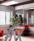 Heavy Duty Ladder Platform Tray And Work Stand Holds 400 Pounds in an office setting with red couches and potted plants.