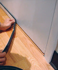 Applying black foam insulation of Soundproof Door Seal And Sweep Kit Built To Kill Background Noise And Seal Gaps under a door.