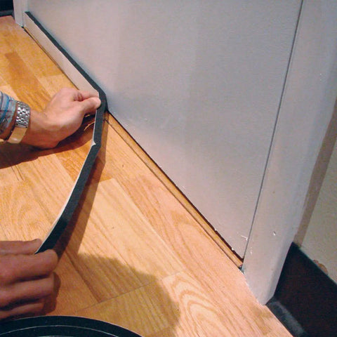 Applying black foam insulation of Soundproof Door Seal And Sweep Kit Built To Kill Background Noise And Seal Gaps under a door.