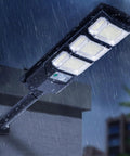 JUDYSSY Outdoor Waterproof Solar Street Light Led Wall Light installed on a wall, illuminated in the rain, outdoor setting.